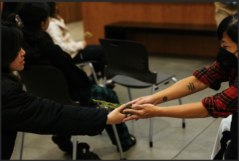 Two people exchanging a bundle of herbs 